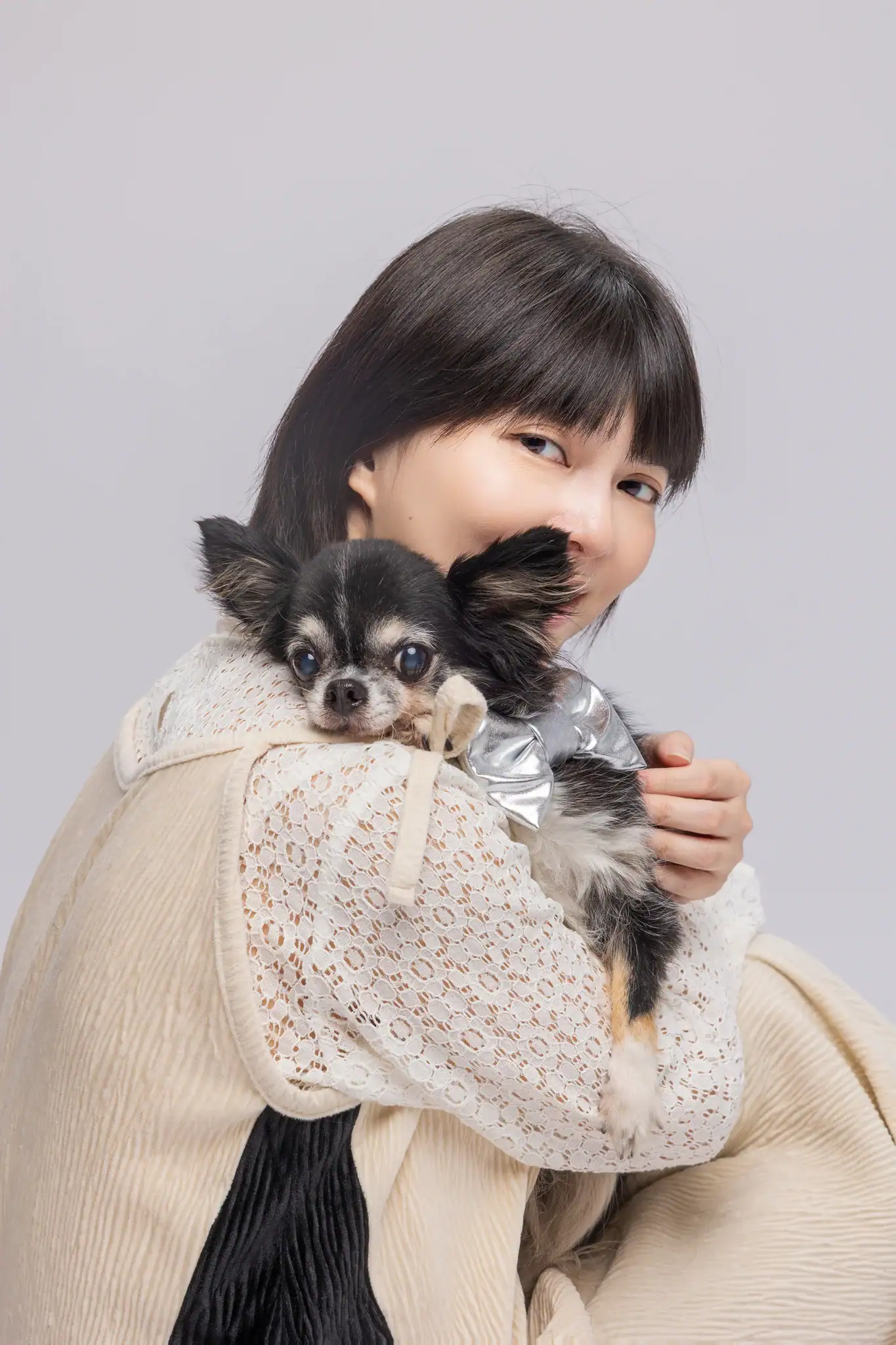 Lisa 與黑棕吉娃娃臉頰相貼，吉娃娃的眼神專注地望向前方，Lisa 則溫柔地笑著看向鏡頭。