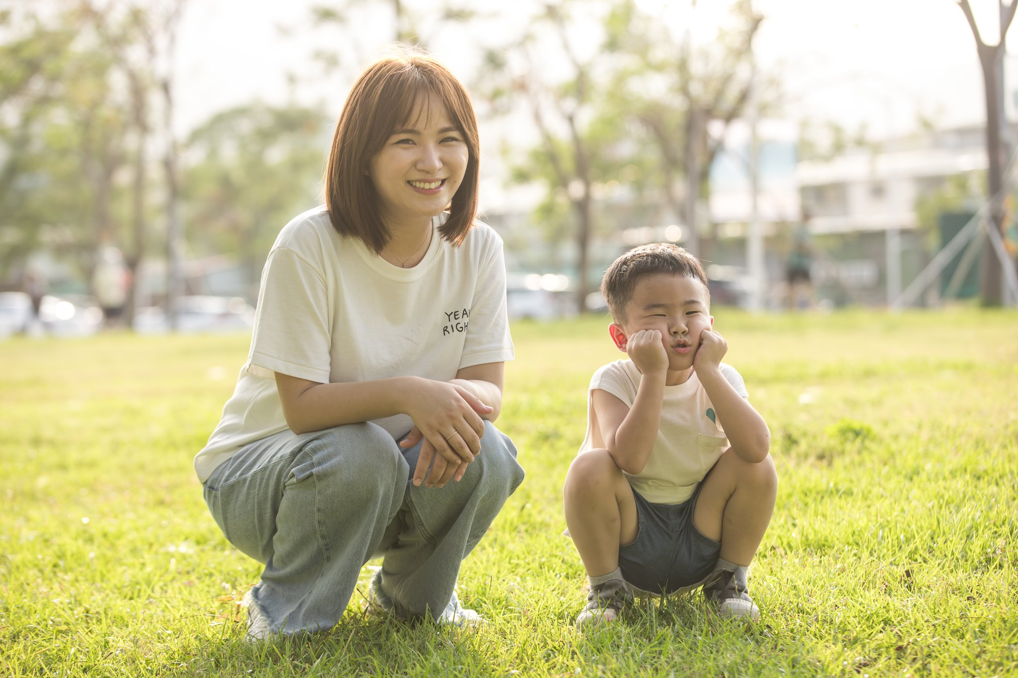 媽媽與品捷一起蹲在草地上，孩子雙手托腮扮可愛