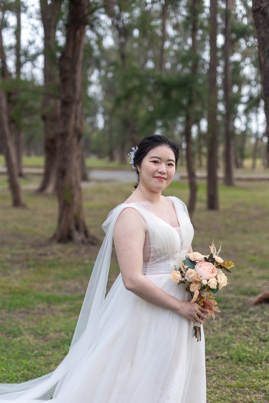 白紗新娘手捧花於林間側身而立的森林系婚紗照,高雄婚紗攝影